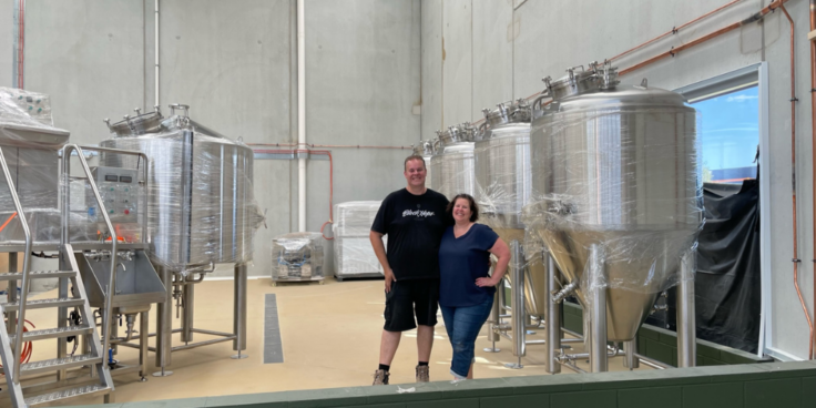Trent (left) and Kylie (right) Butcher standing with their newly delivered brewing equipment